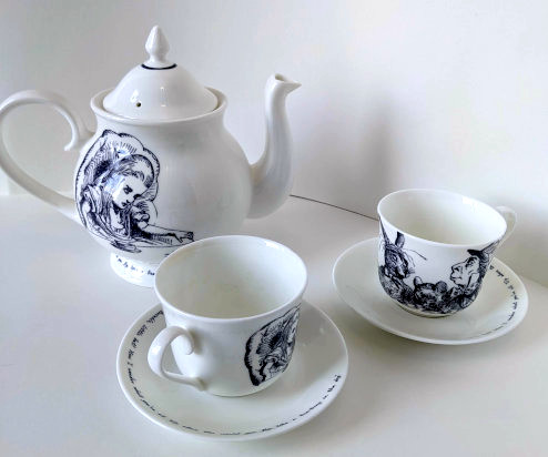 teapot and two teacups with Alice in Wonderland images on them